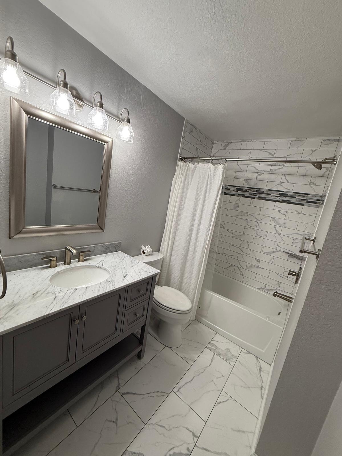 Full bathroom remodel with marble tile and updated vanity